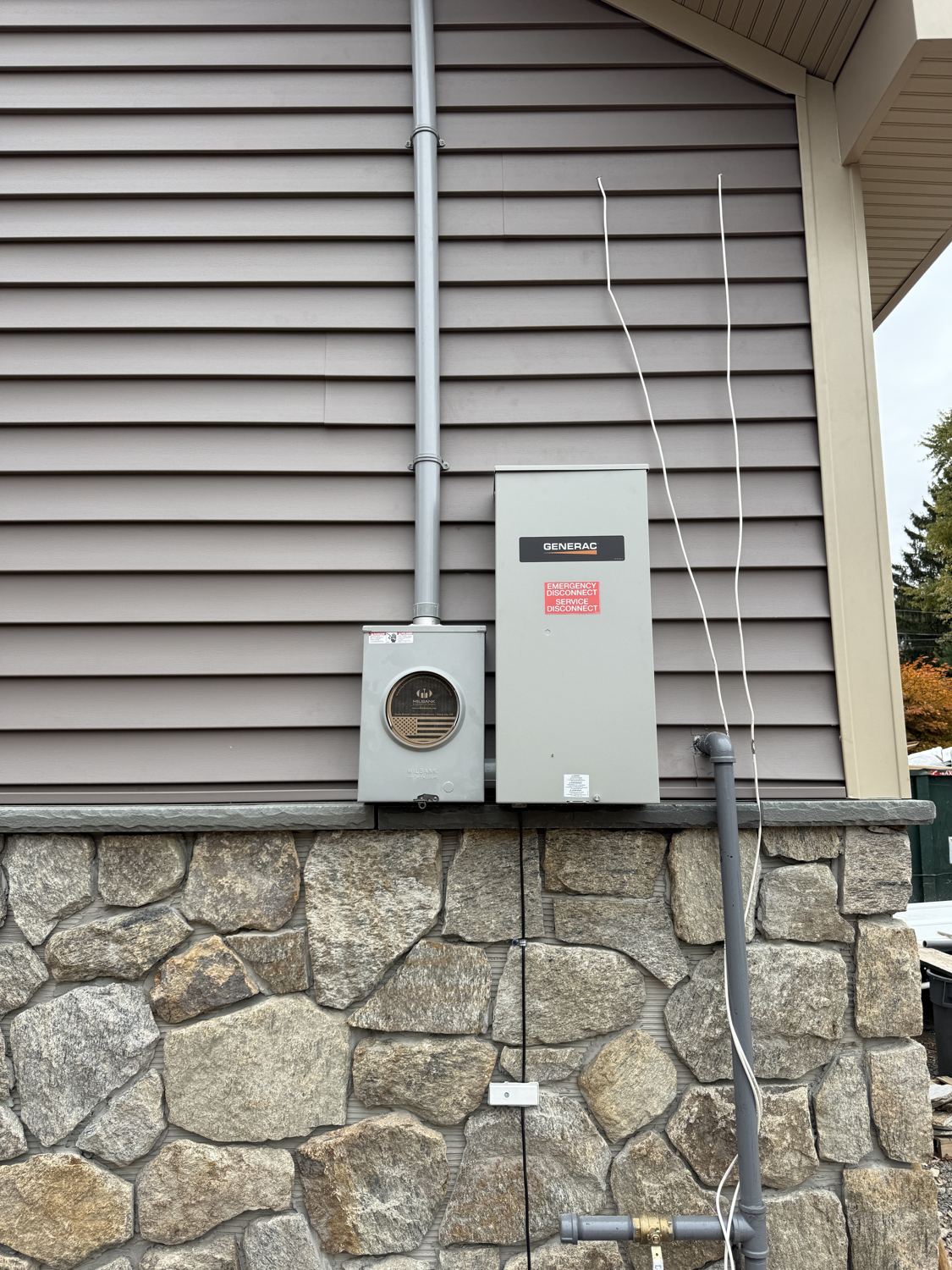 Generac automatic transfer switch and meter installed on a stone-veneer wall by Fuse Electric in North Haledon, NJ